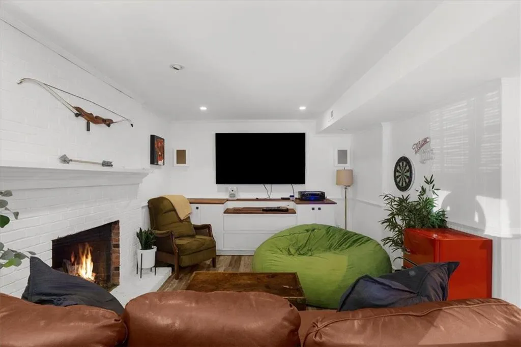 Living area featuring a fireplace, wood finished floors, recessed lighting, and crown molding