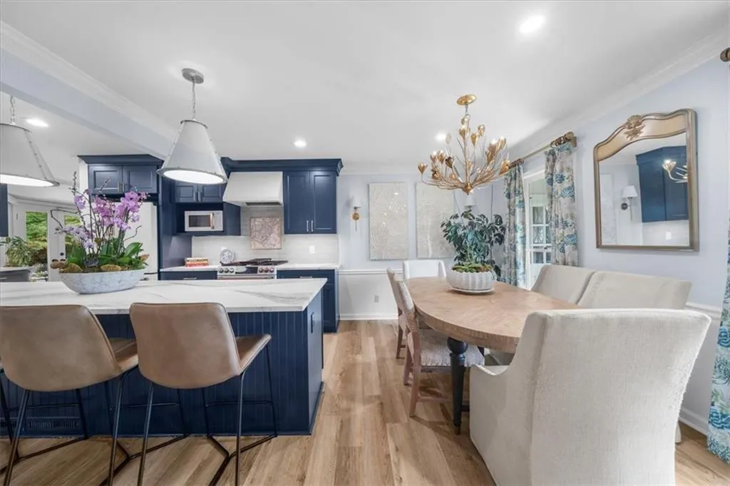 Kitchen featuring blue cabinetry, ornamental molding, light wood-style flooring, backsplash, and freestanding refrigerator