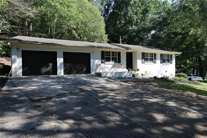 White brick exterior with a two-car garage, black front door, and multiple windows with black shutters