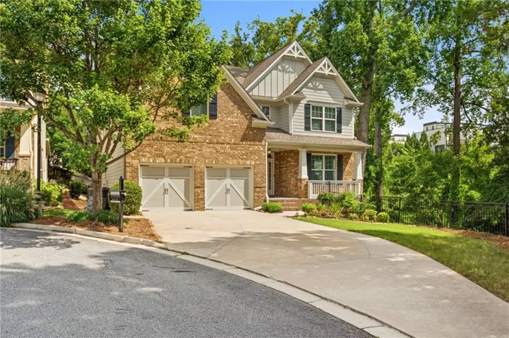 Charming two-story colonial featuring a brick exterior with gable detailing, white-trimmed windows, and a covered entry portico