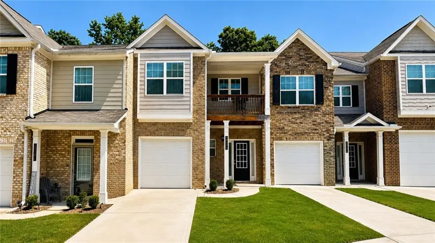 Brick and siding exterior with gabled roof lines, attached garages, covered front entries, and a balcony