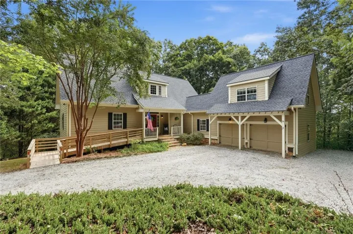 Siding exterior with dormer windows, covered front porch, and an attached two-car garage