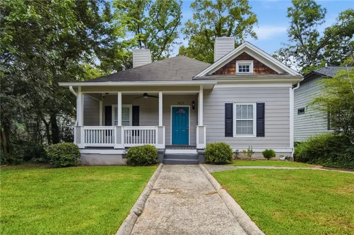 Craftsman-style home featuring a covered front porch, vibrant blue entry door, and decorative window shutters