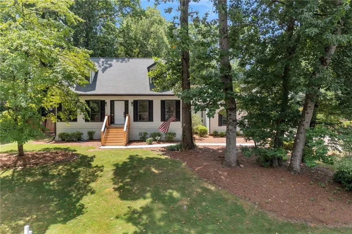 White siding exterior with a dark shingle roof and dormer windows