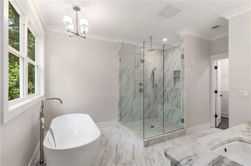 Full bathroom with crown molding, a freestanding bath, a marble finish shower, vanity, and marble finish floors
