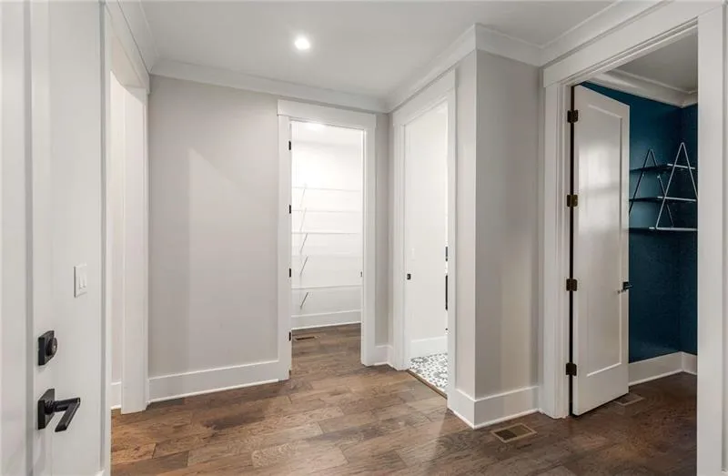 Hallway with dark wood-type flooring, ornamental molding, and recessed lighting