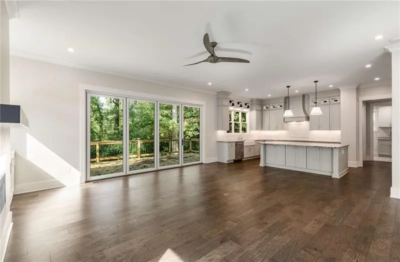 Unfurnished living room featuring crown molding, ceiling fan, dark wood-style flooring, and recessed lighting