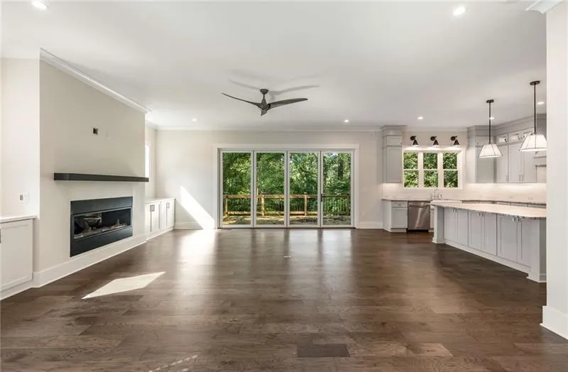 Unfurnished living room with dark wood-style flooring, recessed lighting, crown molding, a glass covered fireplace, and a ceiling fan
