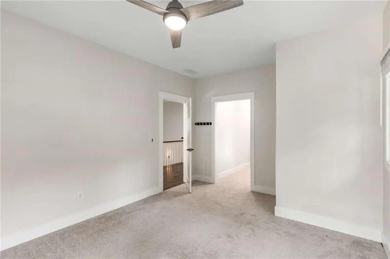 Unfurnished bedroom with light colored carpet and ceiling fan