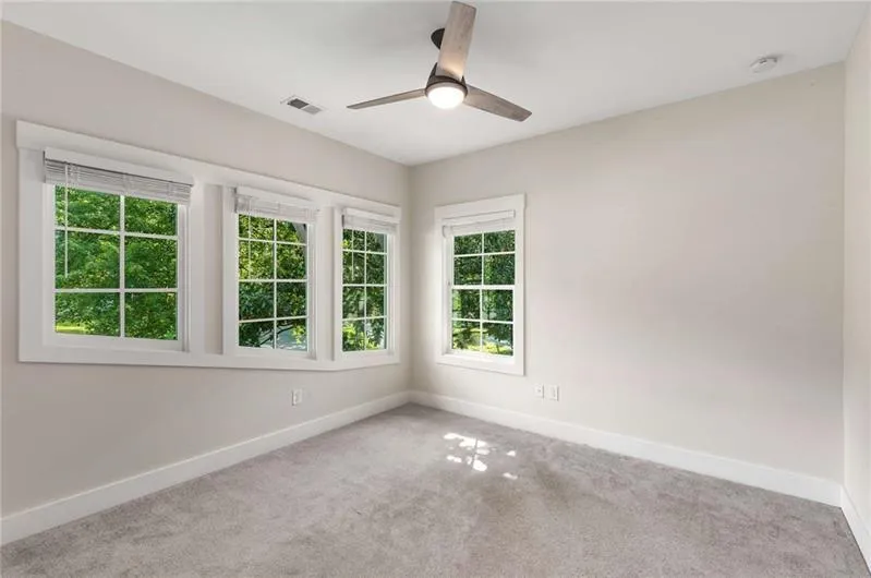 Carpeted empty room featuring baseboards and ceiling fan