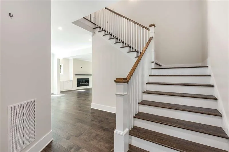 Staircase featuring wood finished floors, a fireplace, and recessed lighting
