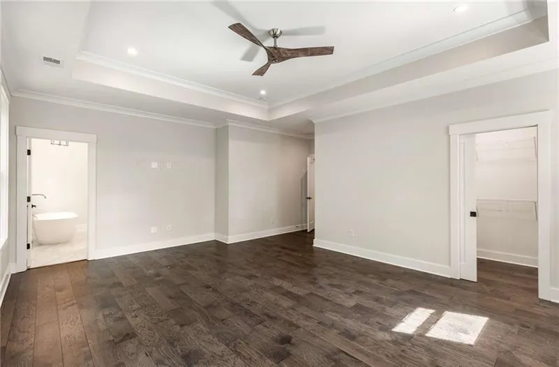 Unfurnished bedroom with a raised ceiling, crown molding, dark wood-type flooring, ceiling fan, and recessed lighting