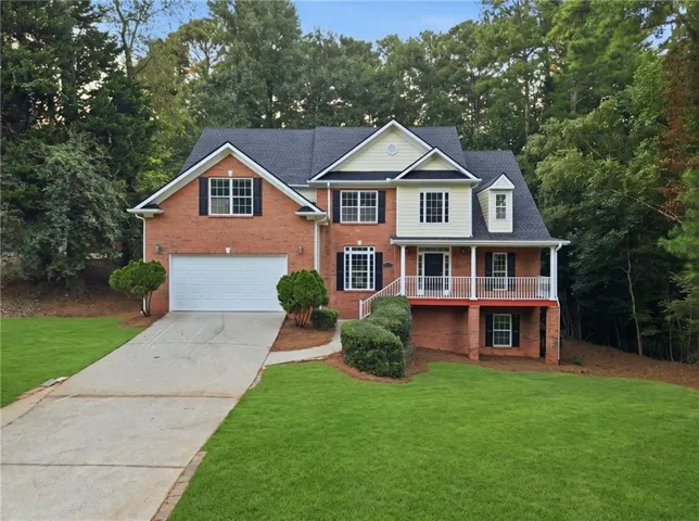 Traditional-style residence featuring a brick and siding exterior, an attached garage, a covered front porch, and a dormer window