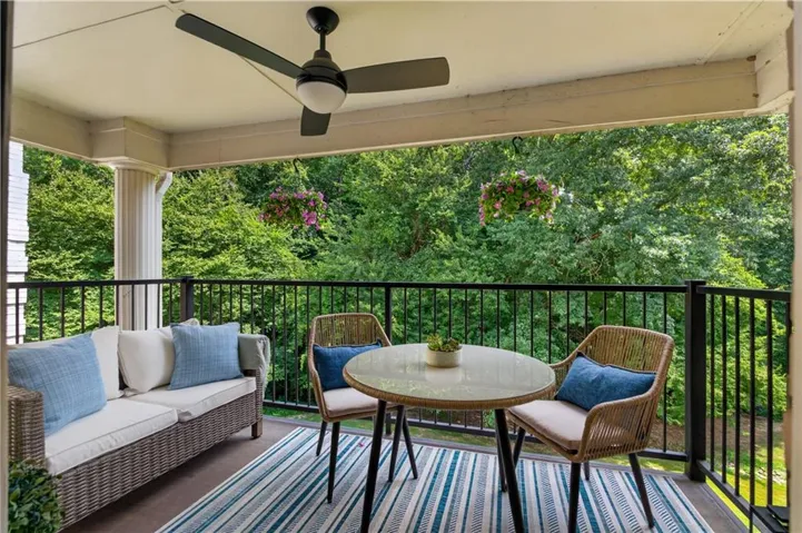 Overlooking a creek and urrounded by mature trees, the spacious covered balcony offers room for both comfortable seating and outdoor dining.