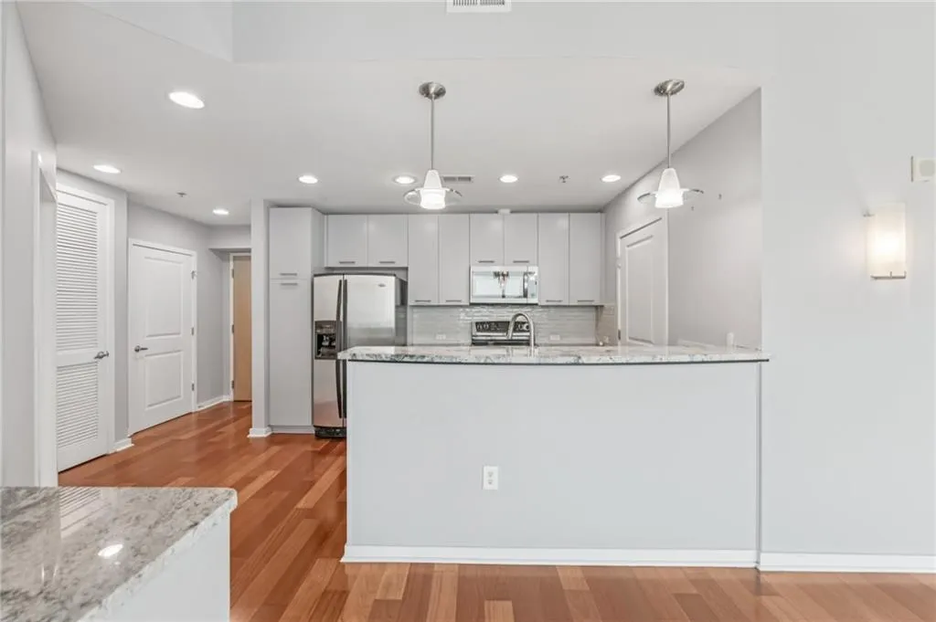 Upgraded kitchen with granite counters, modern backsplash, grey cabinetry, stainless steel appliances, and recessed lighting