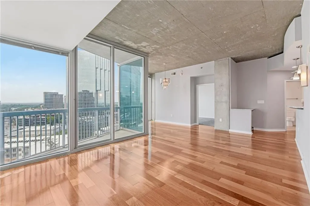 Unfurnished room featuring a wall of windows, wood finished floors, and a view of city
