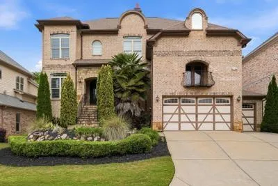 Brick facade residence featuring a multi-level stone staircase, arched entryways, and a private balcony
