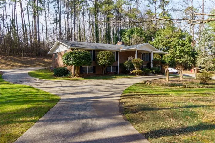Split foyer home featuring brick siding, driveway, a chimney, and a front yard
