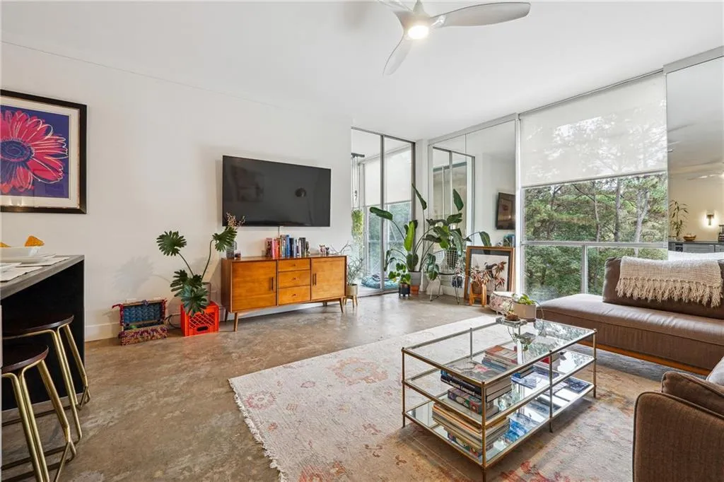 Living area featuring expansive windows, unfinished concrete floors, and a ceiling fan