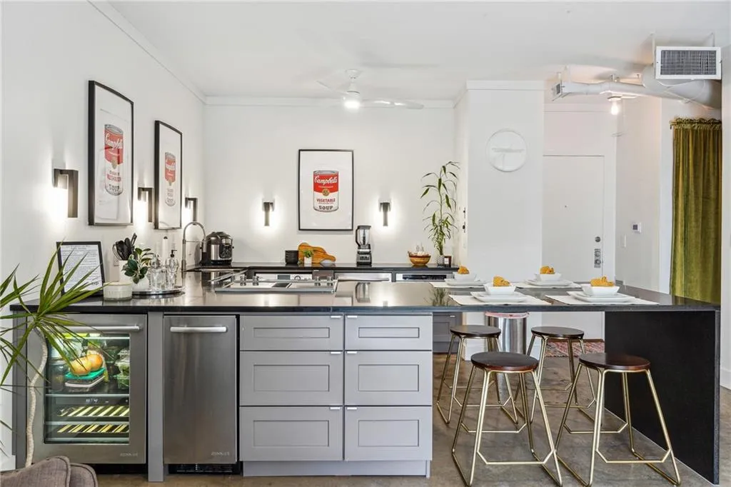 Kitchen with beverage cooler, gray cabinetry, a peninsula, crown molding, and a breakfast bar area