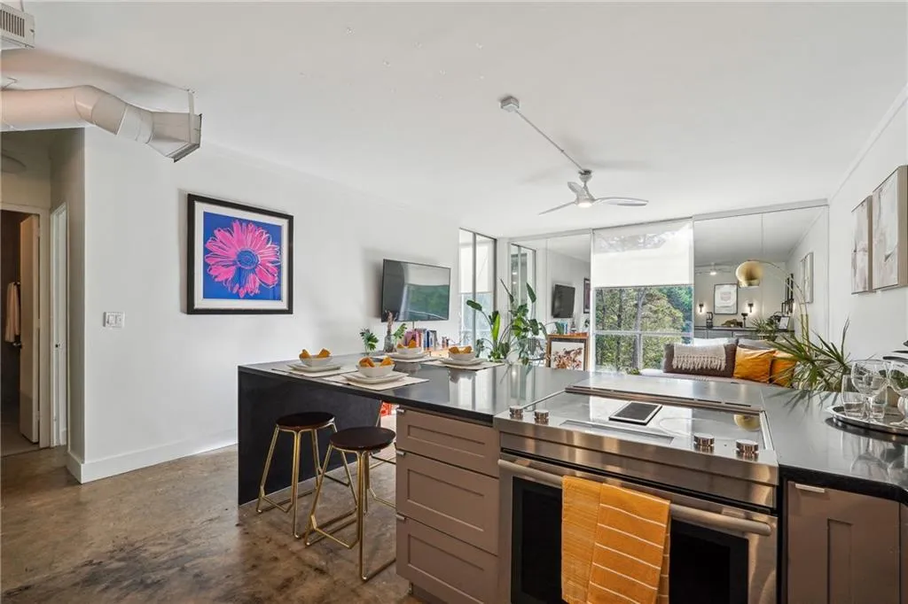 Kitchen featuring electric range, concrete flooring, dark stone countertops, ceiling fan, and open floor plan