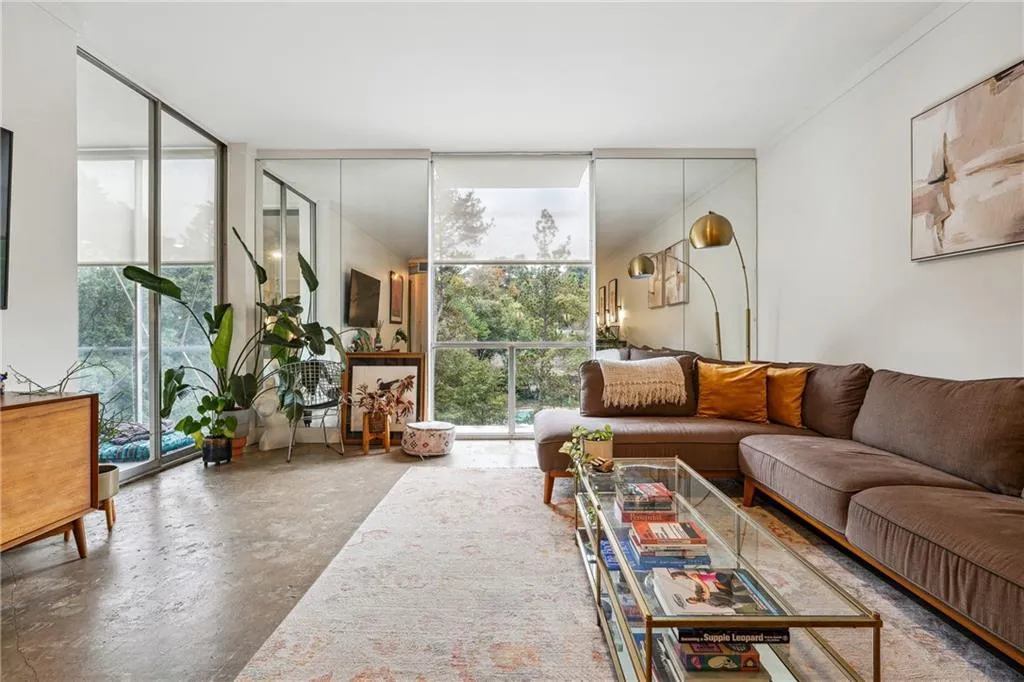 Living area with expansive windows, unfinished concrete floors, and ornamental molding