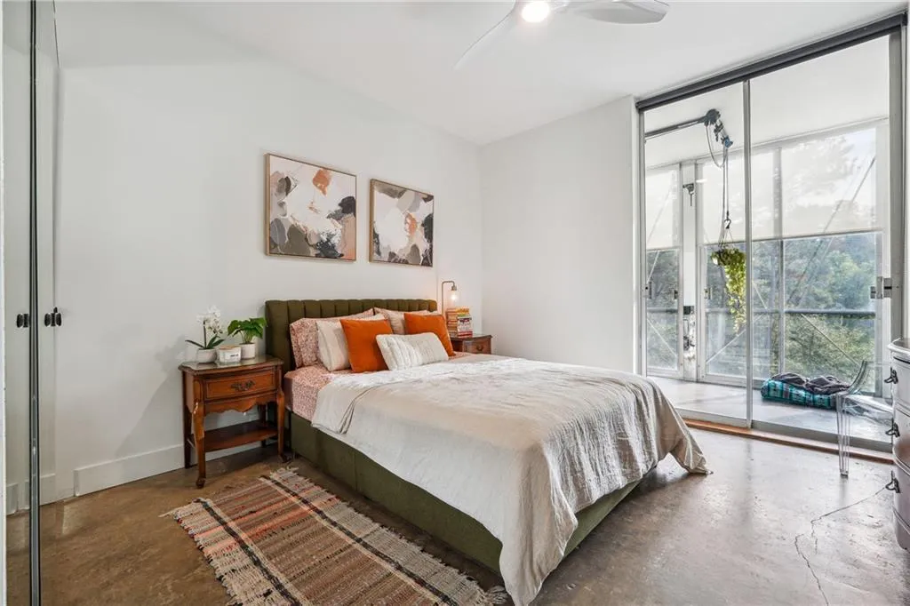 Bedroom featuring concrete flooring, access to exterior, floor to ceiling windows, and ceiling fan