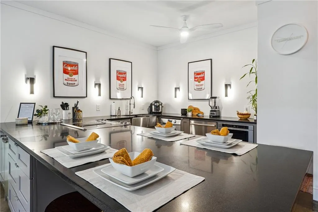 Kitchen with stainless steel dishwasher, ceiling fan, ornamental molding, and dark stone countertops