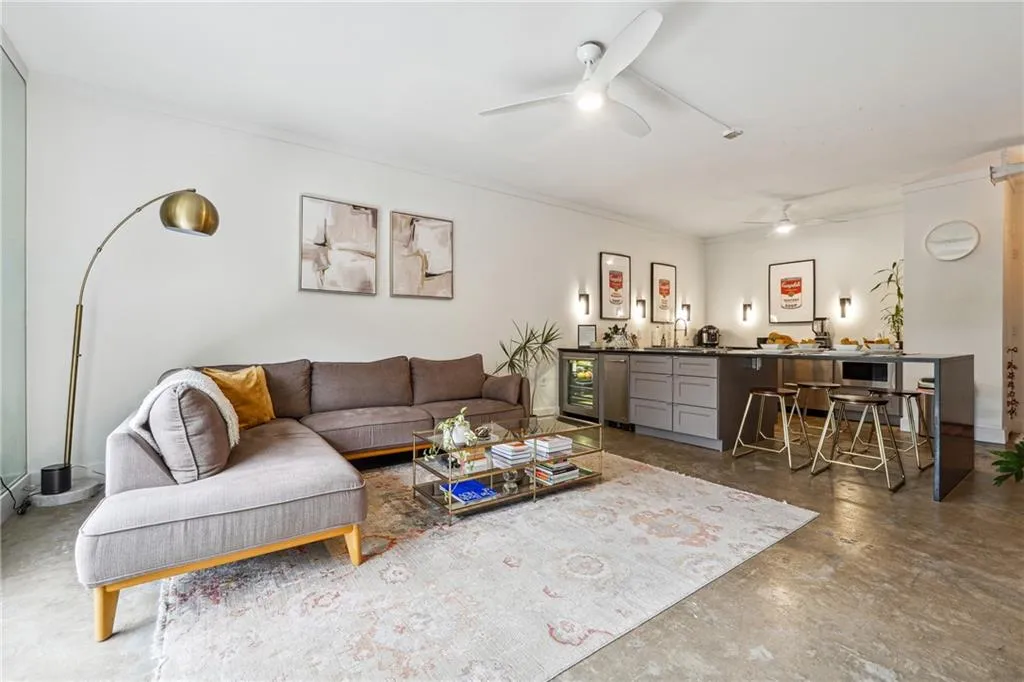 Living room featuring finished concrete flooring, beverage cooler, and ornamental molding