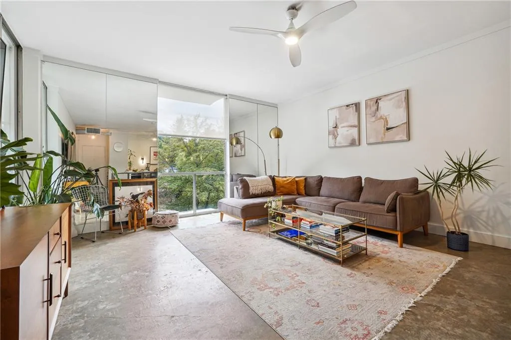 Living area with concrete floors, a wall of windows, ornamental molding, and ceiling fan