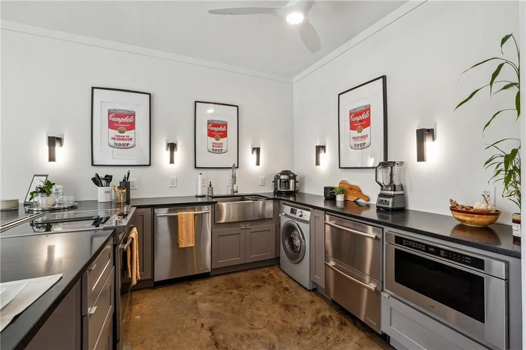 Kitchen featuring stainless steel appliances, washer / clothes dryer, gray cabinets, crown molding, and dark stone countertops
