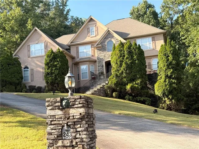 Stucco and stone exterior with a multi-gabled roofline, arched windows, and decorative shutters