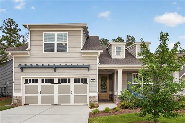 Siding exterior with stone accents, a two-car garage, dormer windows, and a covered front entry