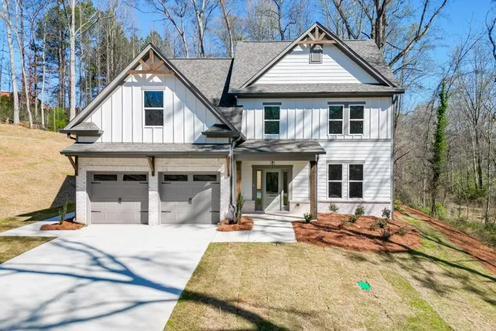 Modern farmhouse exterior featuring white board and batten siding, light brick accents, a gabled roofline, and a two-car garage