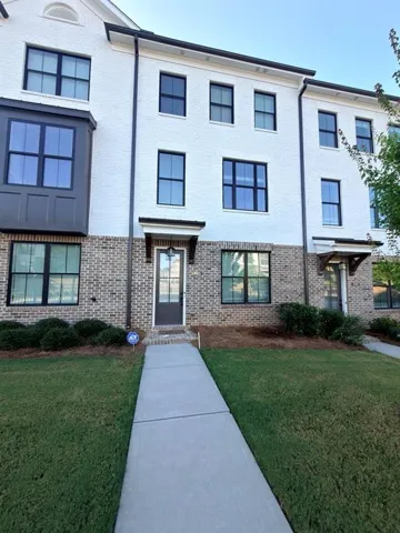 Brick and painted brick exterior with black-framed windows, a prominent bay window feature, and a concrete pathway