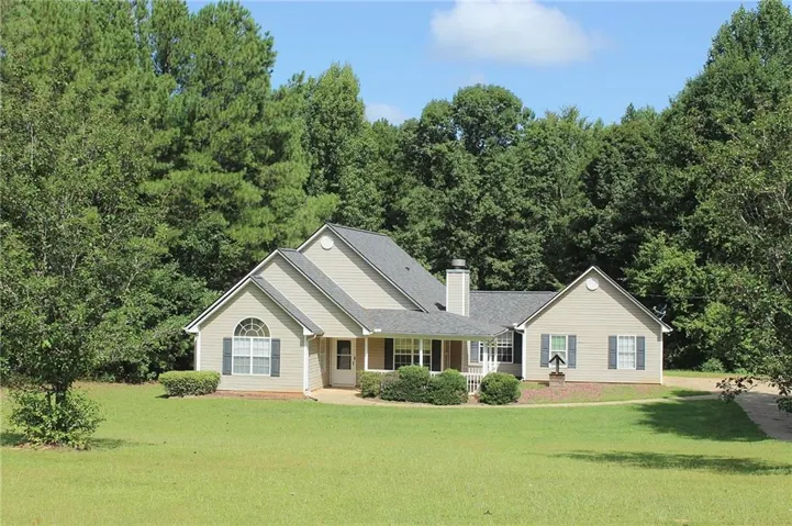 Single-story residence featuring light-colored siding, a covered porch, dark shutters, and a prominent chimney