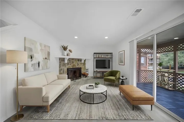 Virtually Staged - Living area featuring a stone-clad fireplace, wood-finish flooring, recessed lighting, and a sliding glass door opening to a screened porch with lattice panels