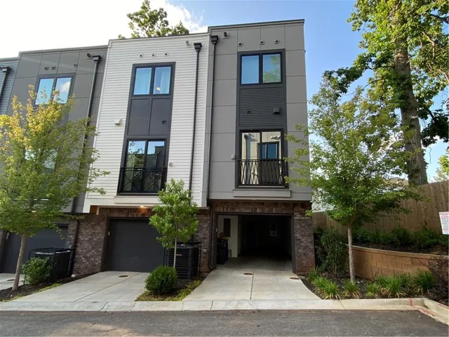 Modern multi-story exterior with mixed material facade, featuring a private balcony and a tandem garage