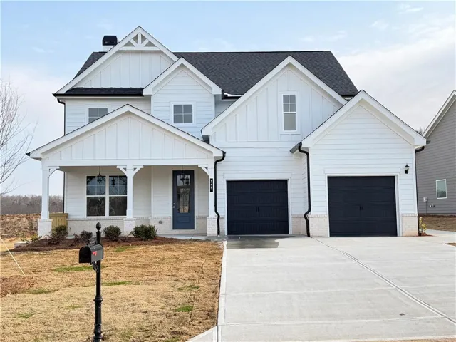 Modern farmhouse featuring board and batten siding, a porch, concrete driveway, a shingled roof, and brick siding