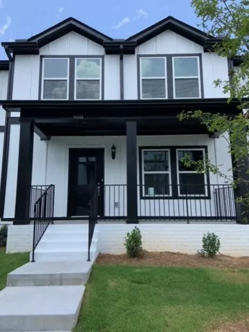 Contemporary exterior with white siding and black trim, featuring a covered porch with black metal railings, a dark entry door, and multi-pane windows