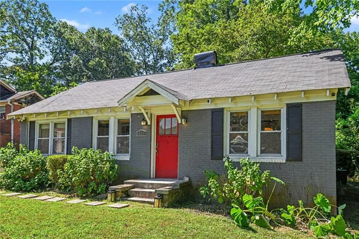 Gray brick exterior with a red front door, white window trim, and dark window shutters