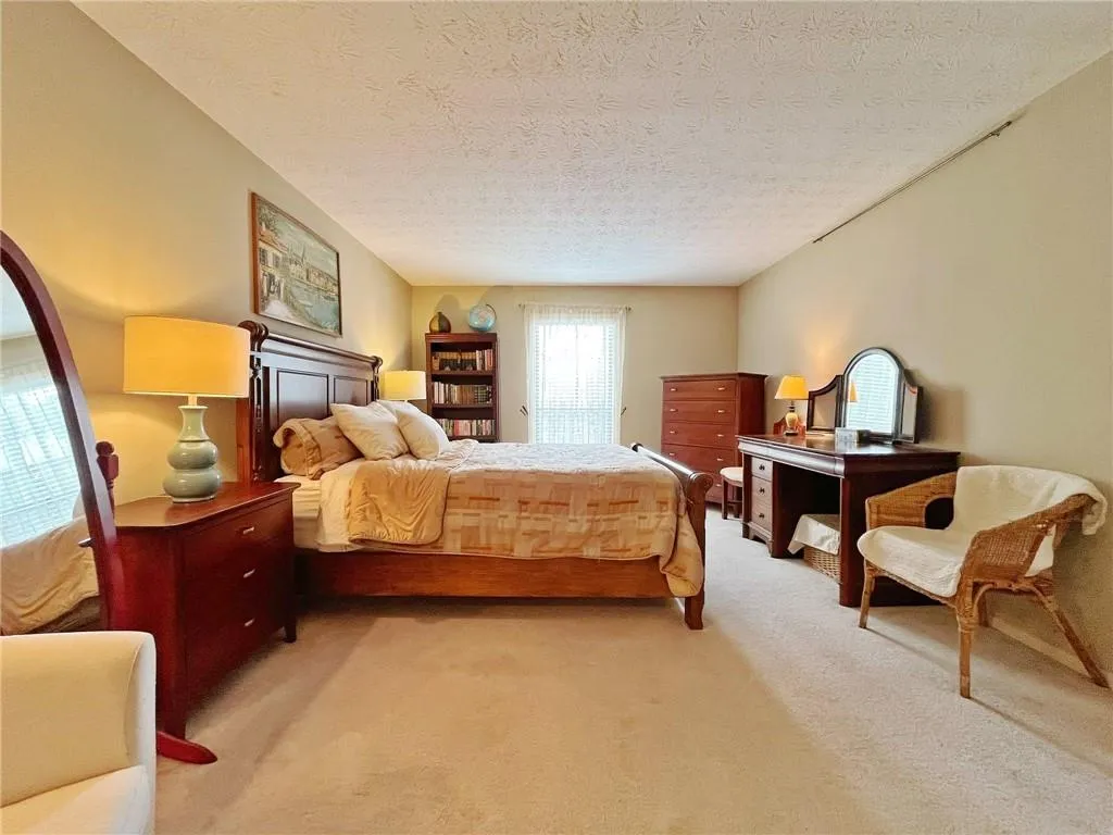 Bedroom with light colored carpet and a textured ceiling