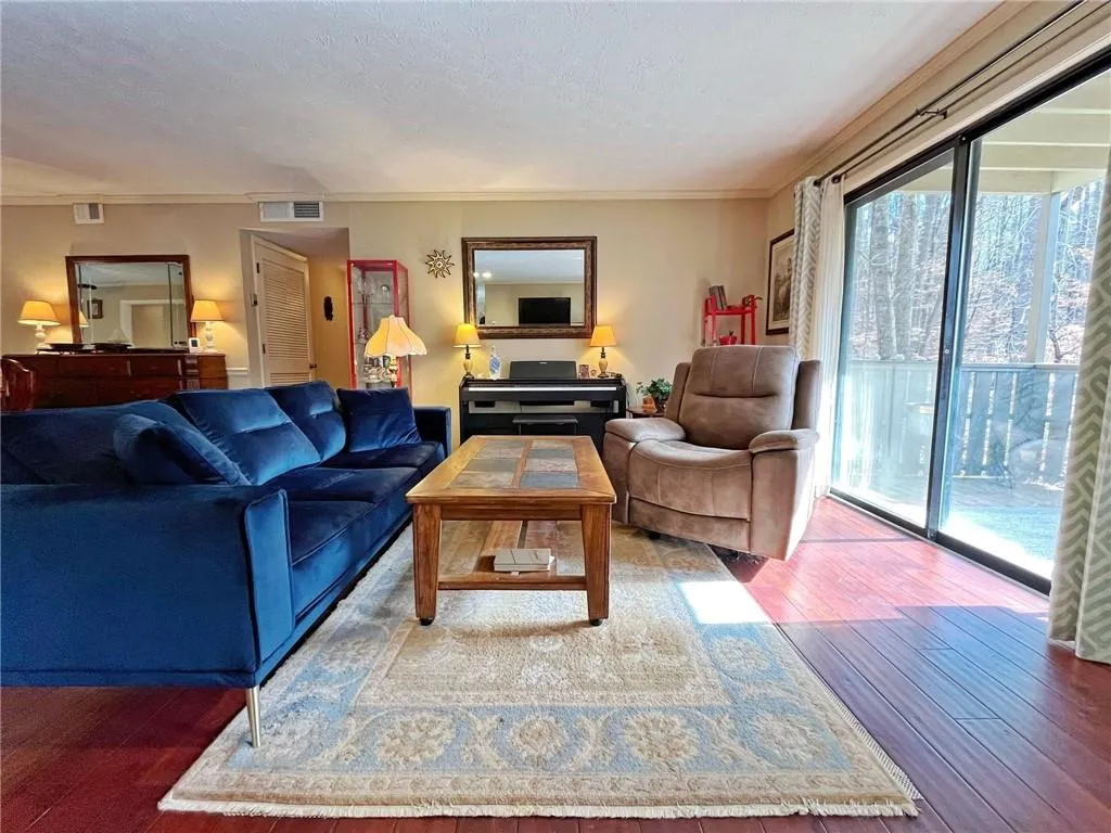 Living room with hardwood / wood-style floors, a textured ceiling, and ornamental molding