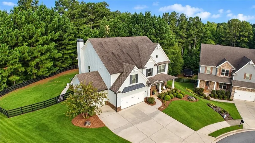 Aerial view showcasing a spacious cul-de-sac home with expansive green lawns, mature wooded surroundings, manicured landscaping, and a private fenced yard.