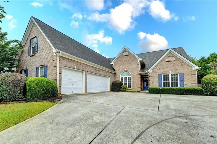 Brick exterior with multiple gables, a two-car garage, established landscaping, and a concrete driveway