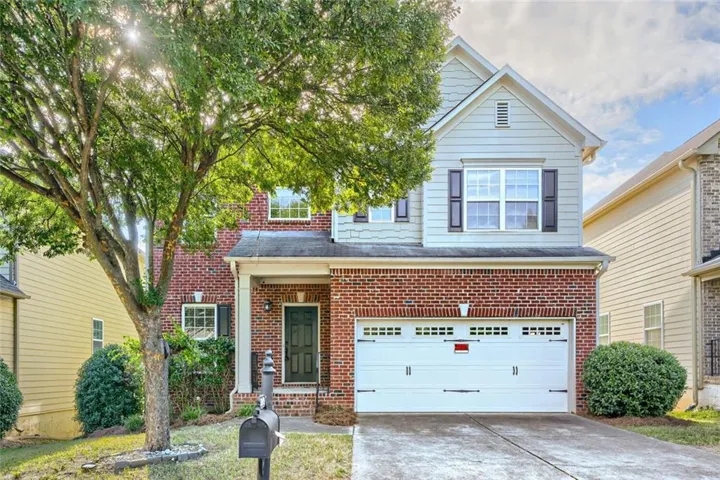 Brick and siding exterior with a covered front porch, an attached garage, and a concrete driveway