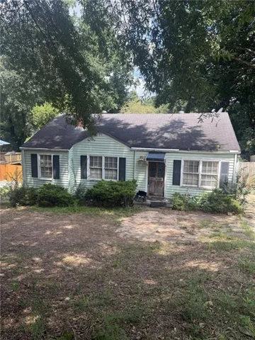 Light green siding exterior with dark shutters, multiple windows, and a dark shingle roof