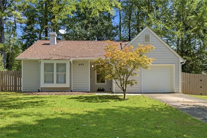 Light-colored siding exterior with a brown shingle roof, attached single-car garage, and a front yard with a paved driveway