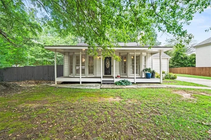 White siding exterior featuring a covered porch, dark entry door with decorative glass, multiple windows, and a driveway