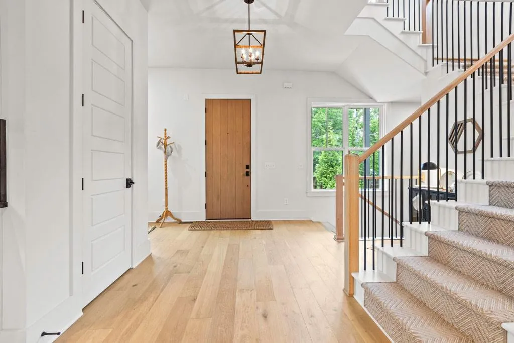 Entryway featuring light wood-style flooring, a chandelier, and stairway